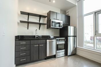 A modern kitchen with stainless steel appliances and black countertops.